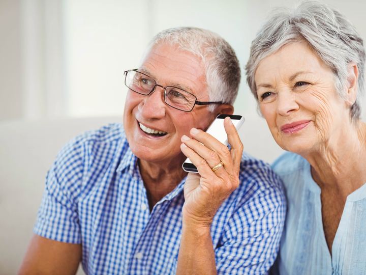 An older couple smiling as they share a phone call