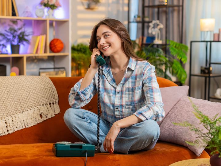 A young woman laughing on her home phone in a bright living room